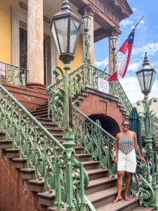 Ali standing on the curved green ironwork staircase outside Market Hall in downtown Charleston