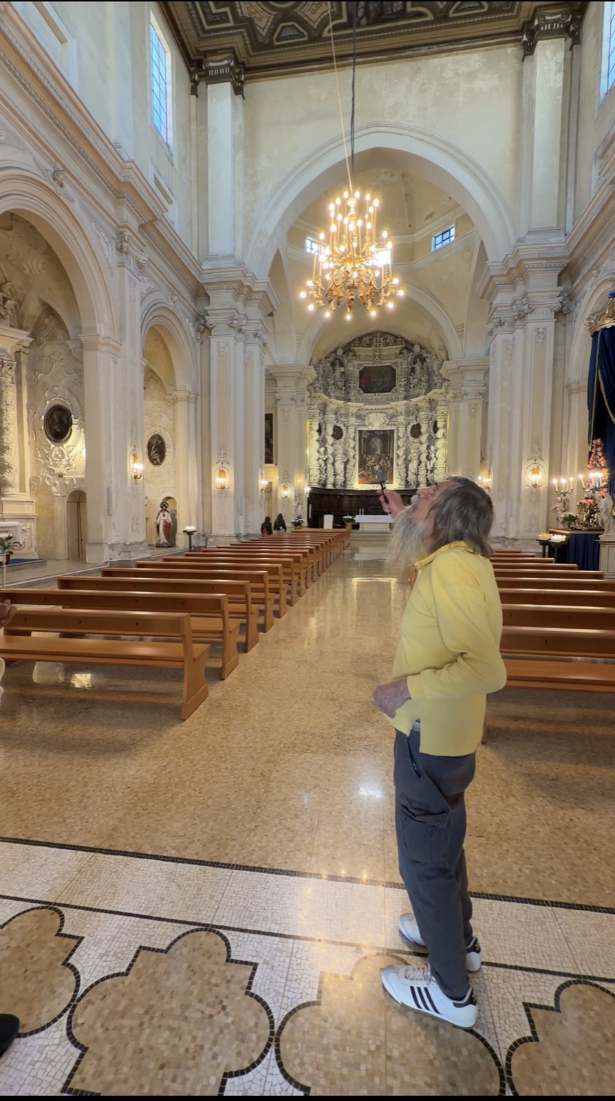 Local historian Antonio pointing up at the ceiling inside a baroque church in Lecce, Puglia