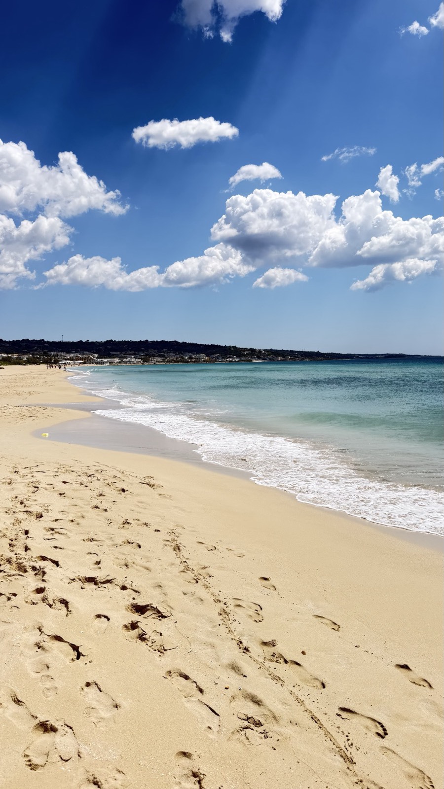 Wide empty stretch of pale sand and turquoise shallow water at Pescoluse beach in Salento, Puglia